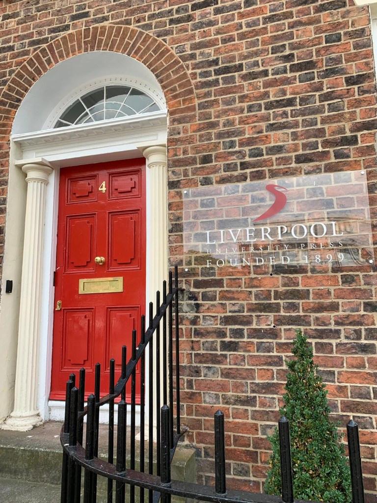 Colour photograph of the entrance to the new Liverpool University Press building on Cambridge Street - a redbrick building with a painted red front door and gold letterbox. Sign on building reads: Liverpool University Press Founded 1899. 