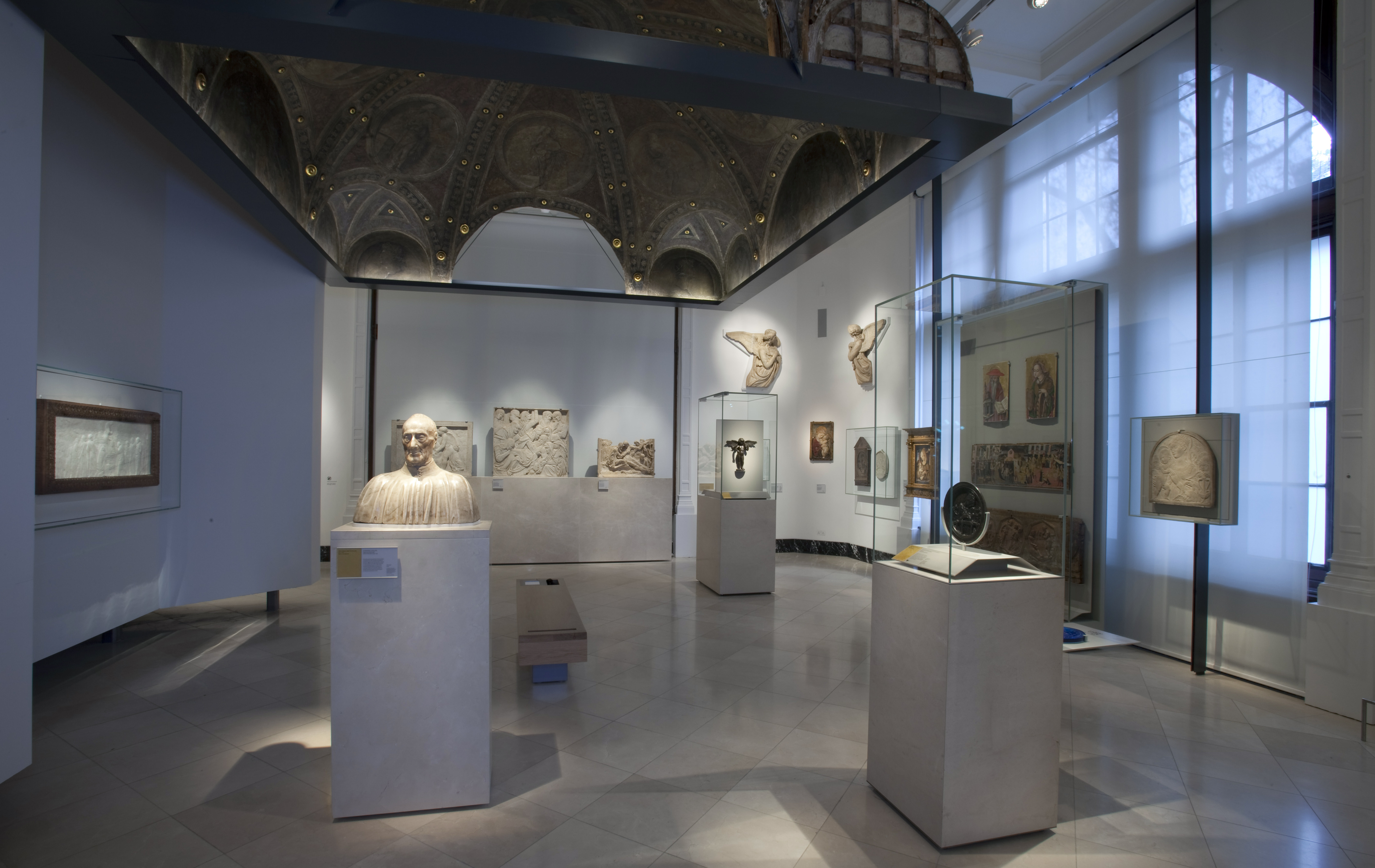View of Gallery 64a, The Robert H. Smith Gallery, Victoria and Albert Museum, London (photo: © Victoria and Albert Museum, London). 

The photograph shows a several artworks in a softly lit exhibition space, some surrounded by glass and mounted on plinths, some mounted  on the wall. All are pieces of sculpture.