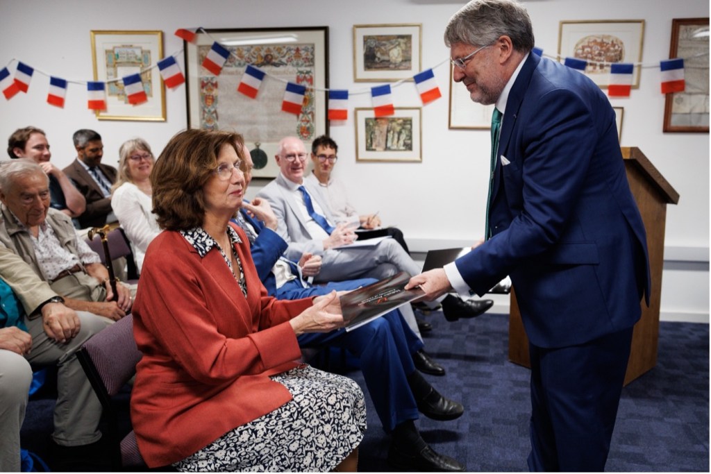 Photograph of Nicholas Cronk presenting H.E. Madame Hélène Duchêne with a copy of Voltaire's recently discovered letter to the eighteenth-century comte d'Alion at the launch of Oxford University Voltaire (OV) in Oxford, June 2026.
