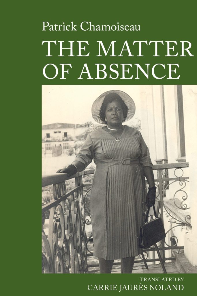 Book cover for The Matter of Absence by Patrick Chamoiseau. The cover has a dark green background with the author’s name and title in large white serif text at the top. At the centre is a black-and-white historical photograph showing a person standing on a balcony with decorative iron railings. The person wears a pleated dress, a wide-brimmed hat and gloves, and holds a handbag. Buildings can be seen in the background beyond the balcony. At the bottom of the cover, white text reads: “Translated by Carrie Jaurès Noland.”