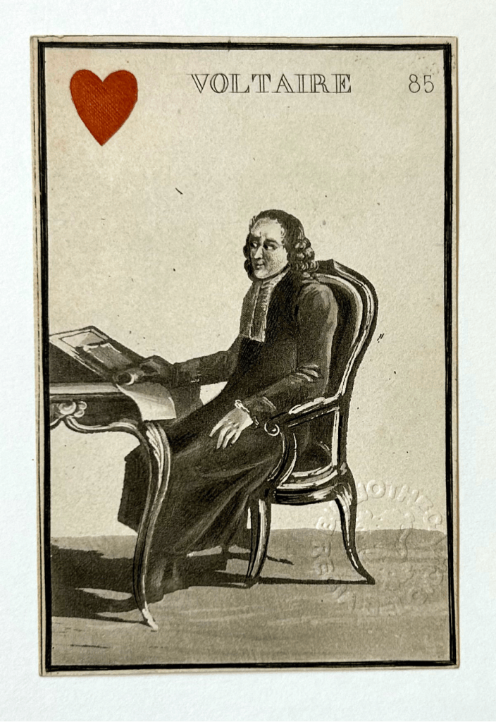 Image of a playing card featuring an illustration of Voltaire sat at a desk. In the top left corner there is a red heart.